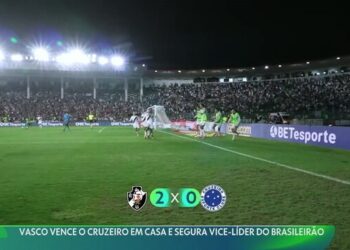 Vasco em destaque no estádio com torcida ao fundo.