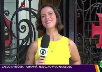 Vlogueira sorridente em frente ao portão preto.