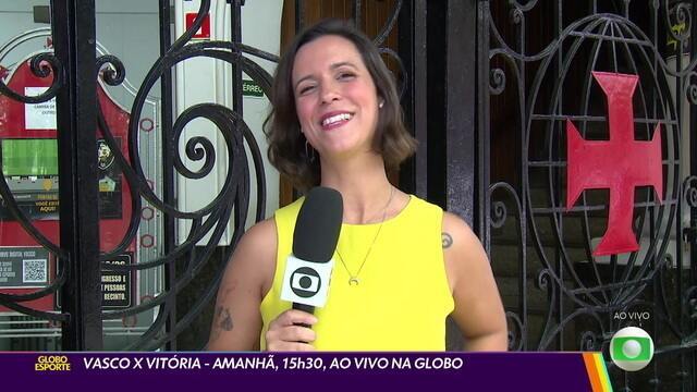 Vlogueira sorridente em frente ao portão preto.