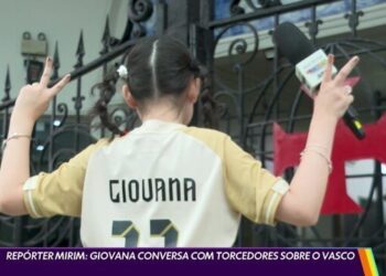 Giovana com camisa do Vasco e microfone na mão.