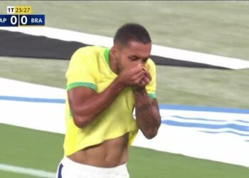 Jogador japonesa com uniforme amarelo cobrindo boca.