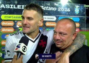 Jogador de futebol sorridente com torcedor após jogo.