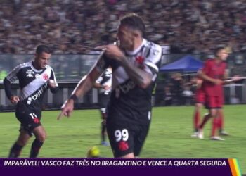 Vasco jogando no estádio com jogadores e torcida ao fundo.