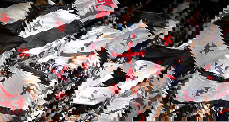 Bandeiras do Vasco sendo agitadas no estádio.