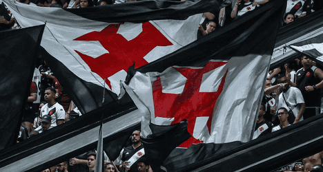 Bandeiras do Vasco being agitated em torcida.