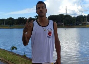 Vascaíno fazendo sinal de paz com lago ao fundo.