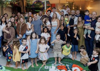 Família comemorando aniversário infantil com crianças e adultos em festa.