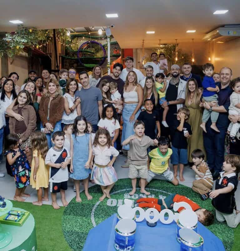 Família comemorando aniversário infantil com crianças e adultos em festa.