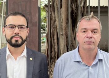 Homens em frente a barreiras de ferro e árvores.