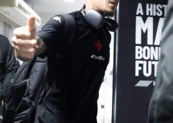 Jogador com mochila e fones de ouvido no aeroporto.