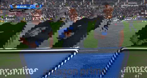 Homens apresentando em estádio com banner da Amazon Prime.