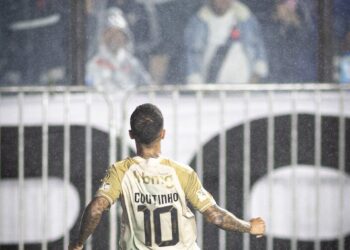 Coutinho comemorando gol no estádio com torcida ao fundo.
