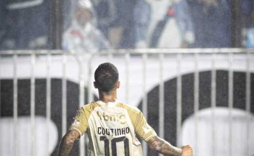 Coutinho comemorando gol no estádio com torcida ao fundo.