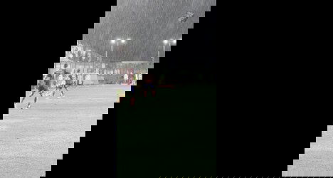 Jogadores treinando no campo à noite.