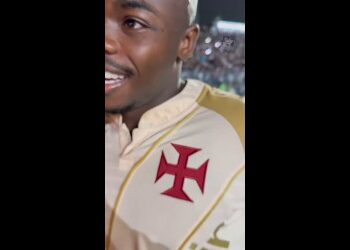 Jogador do Vasco com uniforme branco e escudo vermelho.