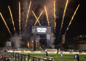 Foguetes iluminando o céu durante partida de futebol.