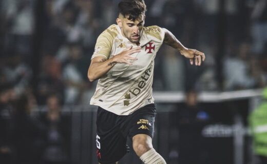 Jogador de futebol com uniforme do Vasco, controlando a bola em campo.