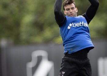 Guarda de futebol segurando bola, durante treino ao ar livre.