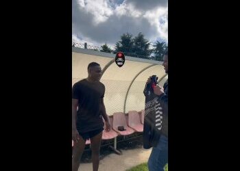 Homem recebendo camisa do Vasco em treino ao ar livre.