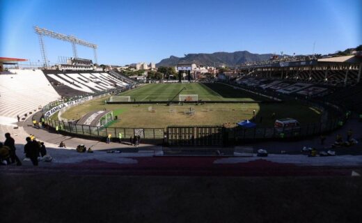 Estádio do Vasco da Gama vazio, com gramado e arquibancadas vistas de dentro.