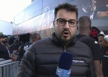 Homem com óculos e microfone na mão.