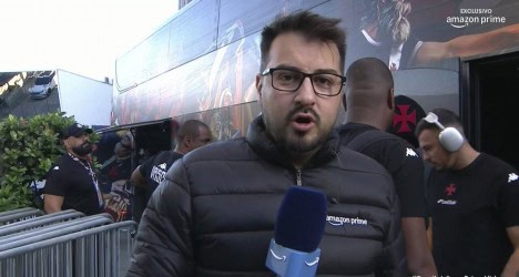 Homem com óculos e microfone na mão.