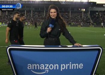 Repórter com microfone no estádio.