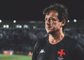 Homem com camiseta do Vasco, estádio ao fundo.