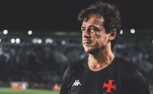 Homem com camiseta do Vasco, estádio ao fundo.
