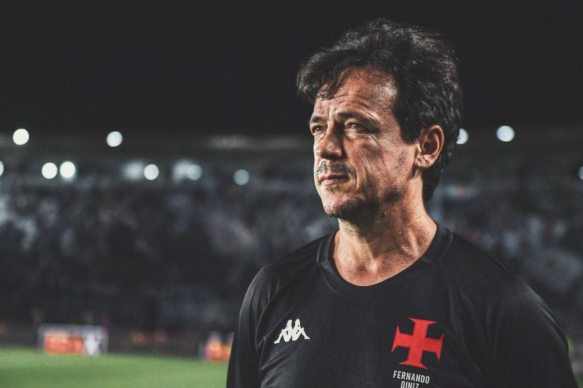 Homem com camiseta do Vasco, estádio ao fundo.