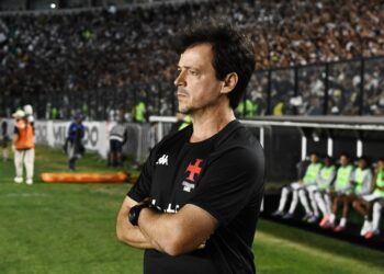 Imagem de técnico do Vasco com expressão pensativa no estádio.