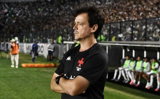 Imagem de técnico do Vasco com expressão pensativa no estádio.
