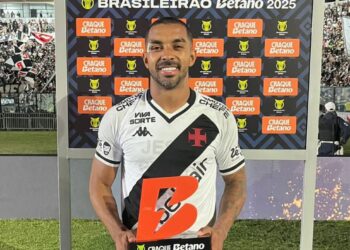 BRAZILIAN SOCCER PLAYER APPEARS WITH VASCO JERSEY AND TROPHY AT CEREMONY.