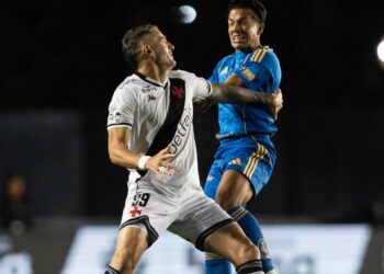 Jogadores de futebol brigando pelo bola em campo.