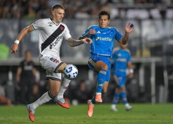 Jogadores do Vasco e adversário disputando a bola no campo.