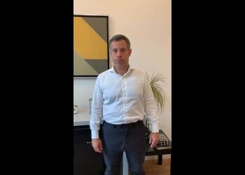 Homem branco de terno em escritório moderno.