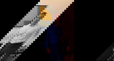 Homem branco de terno em escritório moderno.