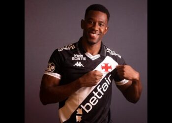 Jogador do Vasco sorrindo e apontando para o escudo.