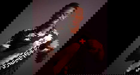 Jogador do Vasco sorrindo e apontando para o escudo.