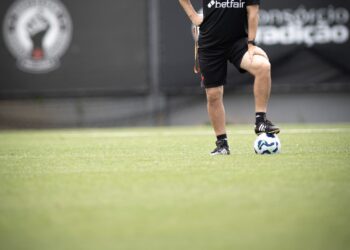 Futebolista treinando no campo com bola nos pés.