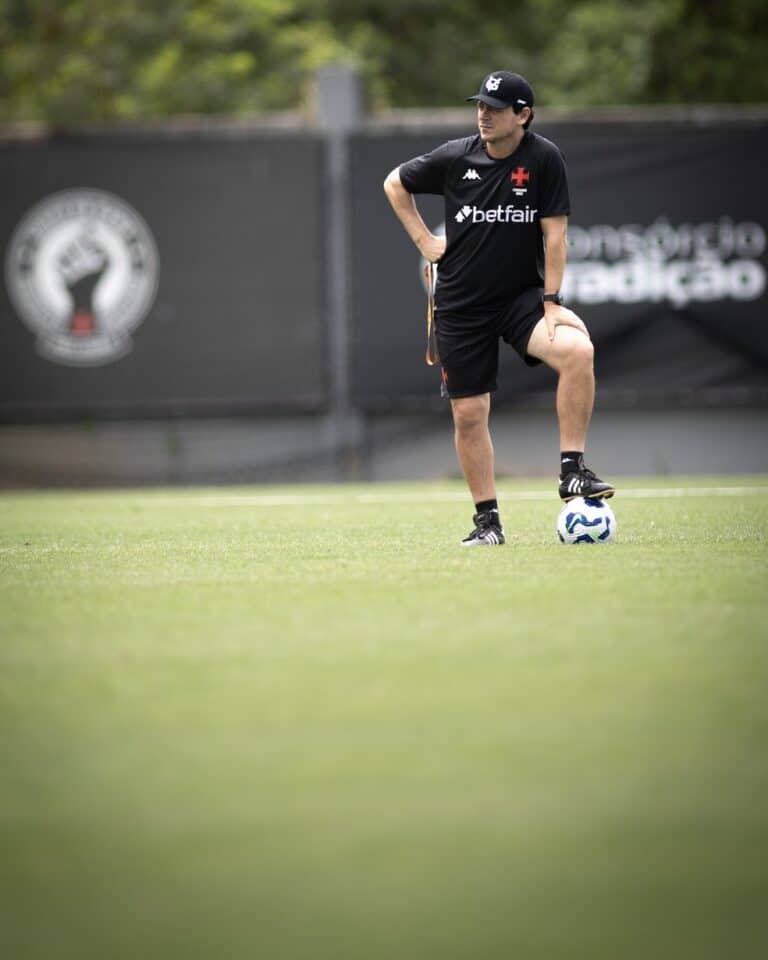 Futebolista treinando no campo com bola nos pés.