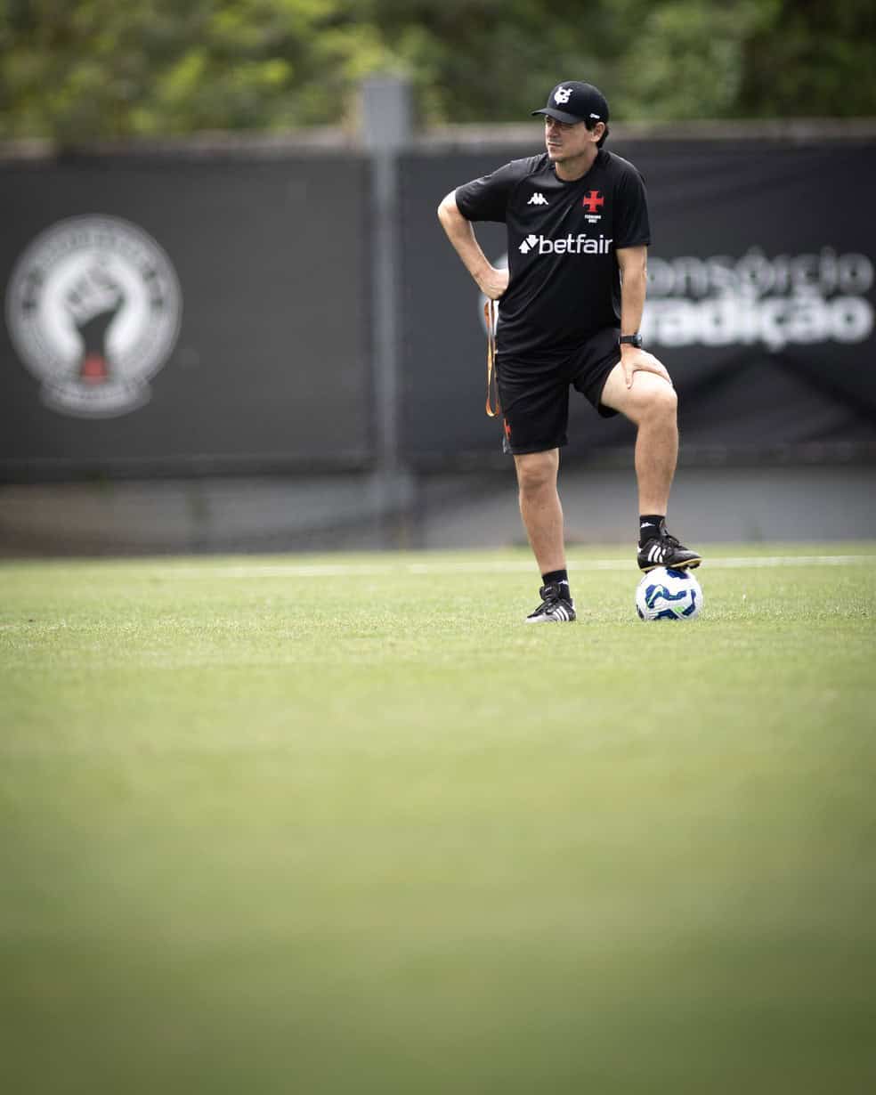 Futebolista treinando no campo com bola nos pés.