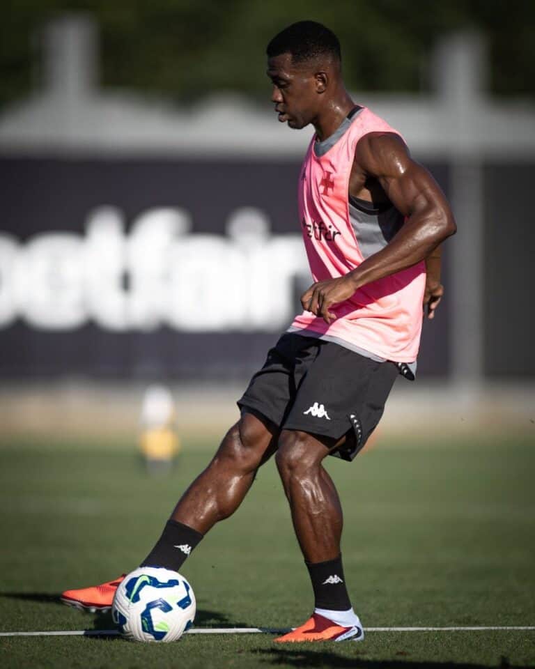 Jogador de futebol treinando com a bola no campo.