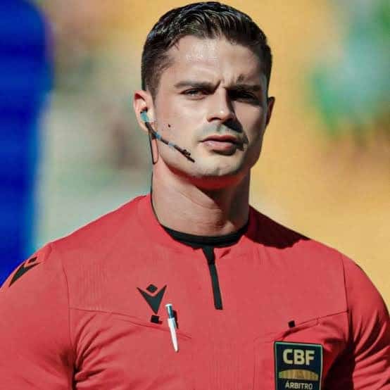 Árbitro de futebol com uniforme vermelho e microfone.