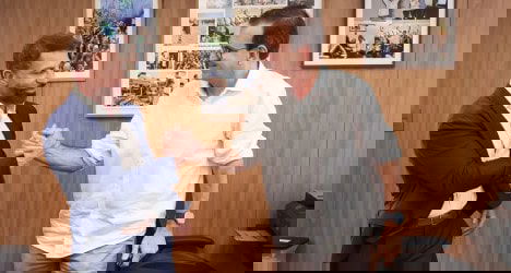 Famosos trocando aperto de mão em reunião.