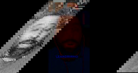 Homem com barba usando fones de ouvido vermelhos.