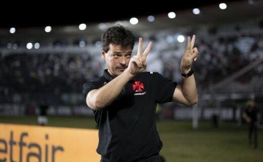 Homem fazendo sinal de paz com as mãos no estádio.