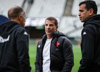Treinador do Vasco conversando com membros da equipe no estádio.