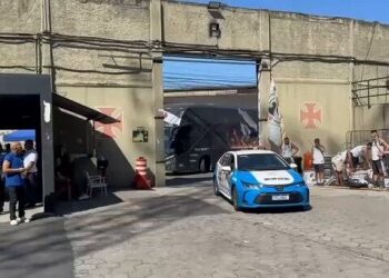 Veículos e pessoas na rua próxima a muro inicial.