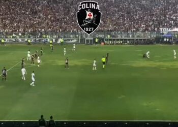 Jogadores em campo durante partida de futebol no estádio.